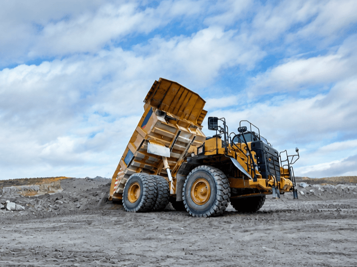 Large yellow mining truck with a raised dump bed at a mine site.