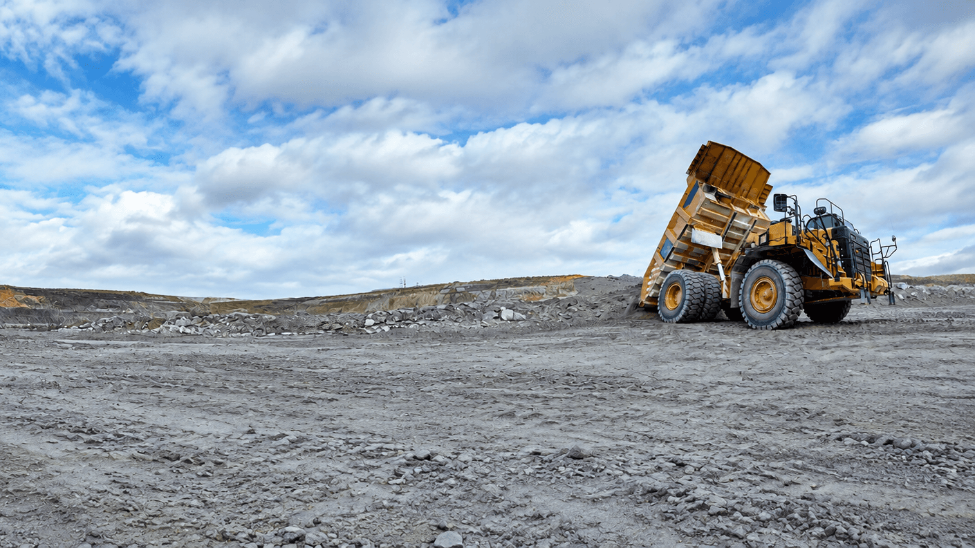 Large yellow mining truck with a raised dump bed at a mine site.