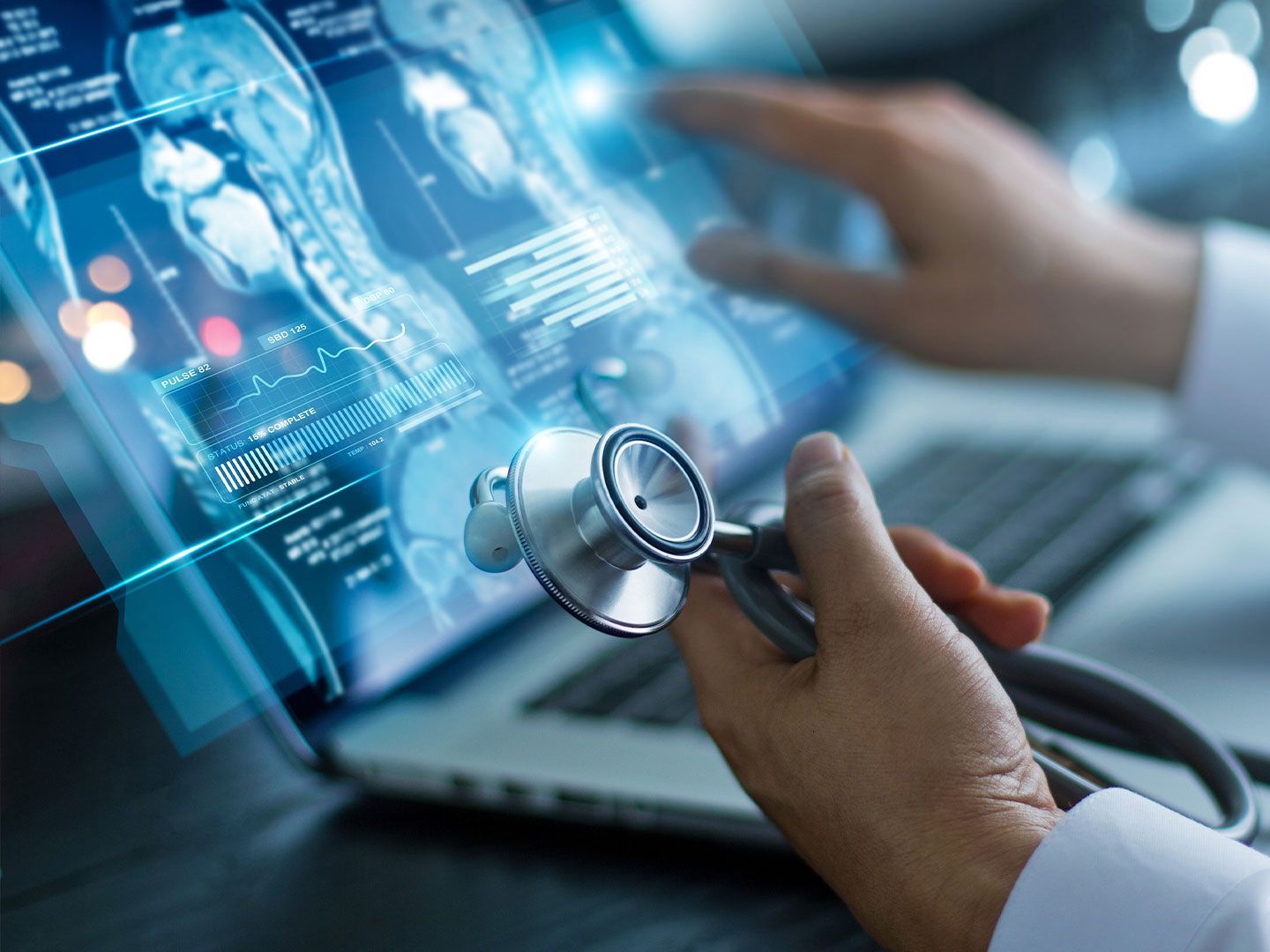 Arzt hält Stethoskop und interagiert mit digitalen medizinischen Bilddaten auf einem Laptop