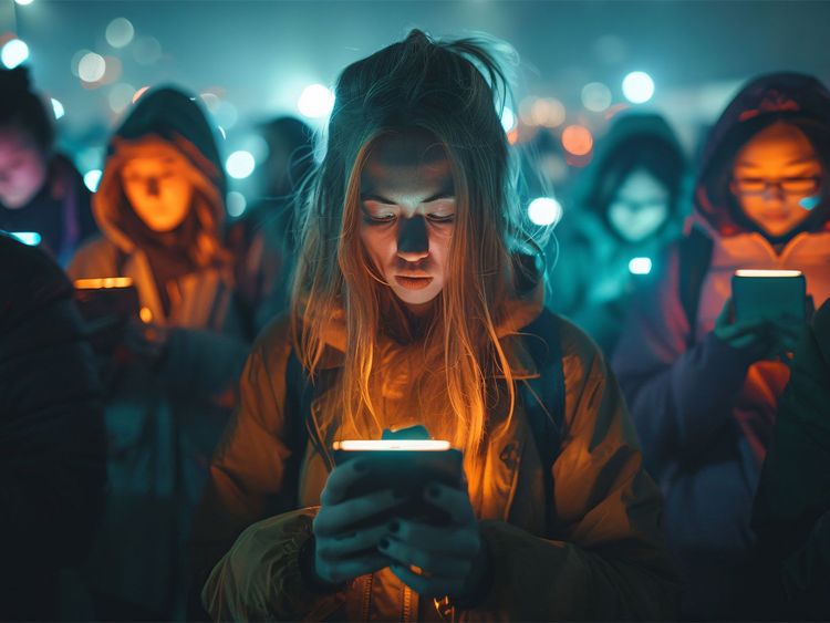 Gruppe von Menschen in dunkler Umgebung, die auf ihre Smartphones schauen, beleuchtet von den Bildschirmen.
