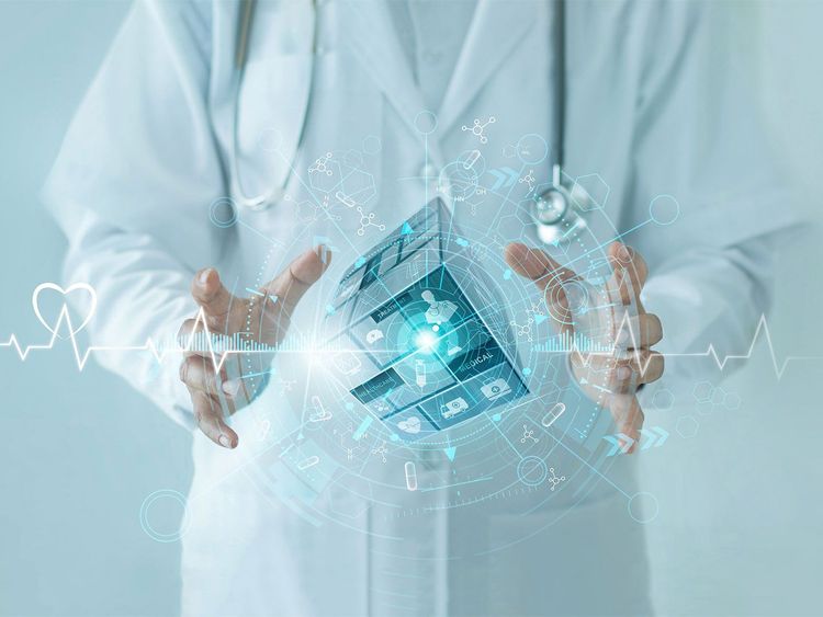 Arzt in weißem Kittel mit Stethoskop vor Brust hält Hände um schwebenden, transparenten digitalen Würfel mit medizinischen Symbolen und Datenvisualisierungen